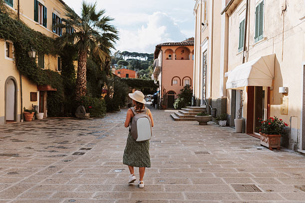 istock Rear view of woman with sun hat carrying a backpack exploring charming town square 2223993349