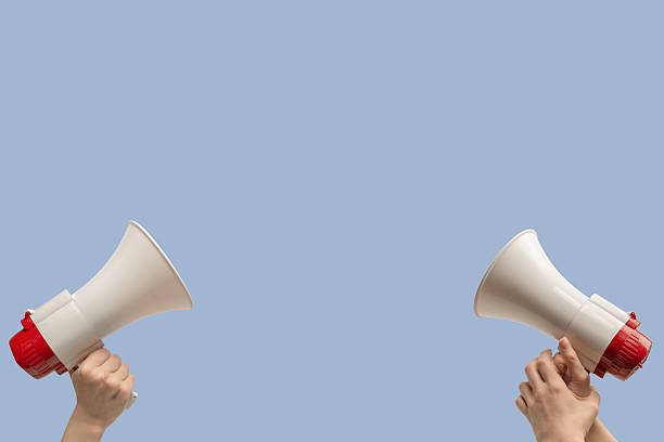 Megaphone in woman hands on a blue background.  Copy space.