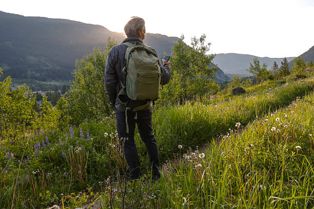 istock Senior hiker uses mobile phone in mountain meadow 2223995677