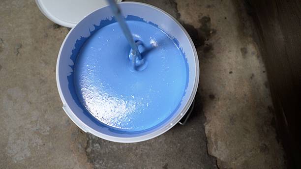 istock Mixing blue paint in bucket with mixing paddle on construction site 2223998724