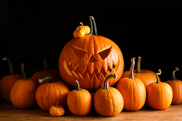 istock Carved jack-o-lantern surrounded by mini orange pumpkins 2224003722