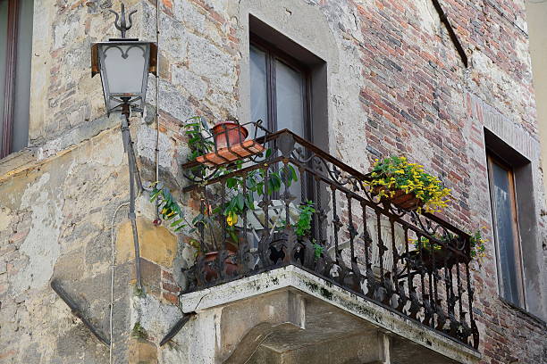 Wrought-iron railing balcony on a red brickwork wall on Vicolo della Via Nuova, corner with Via di Voltaia nel Corso. Montepulciano-Tuscany-Italy-044 stock photo