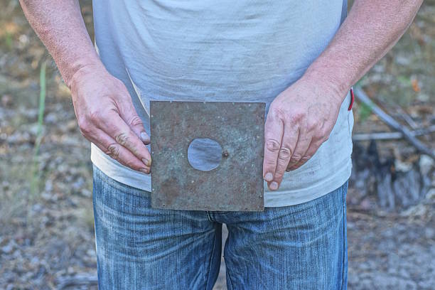 hands man holding one old gray square rusty metal plate with round hole on summer street