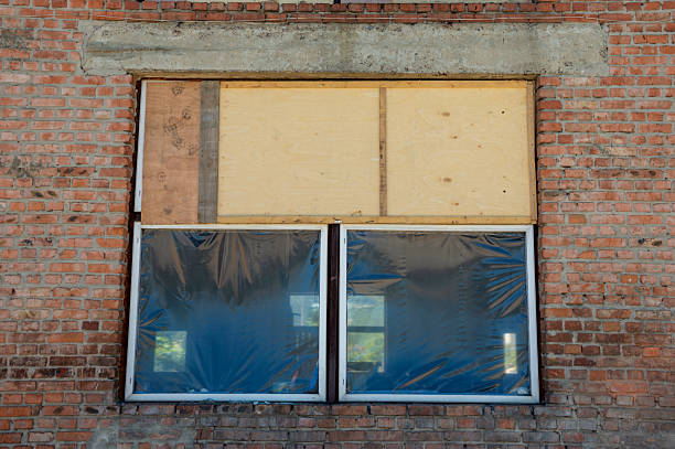 istock Boarded windows are visible on a brick building at a construction site, showcasing unfinished renovations in broad daylight 2224007147
