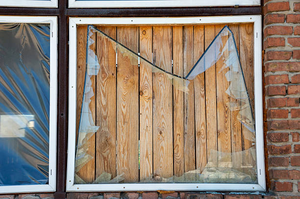 A wooden window, painted white, has one of its six panes of glass missing because a criminal threw a stone at it. Something broken. Psychology