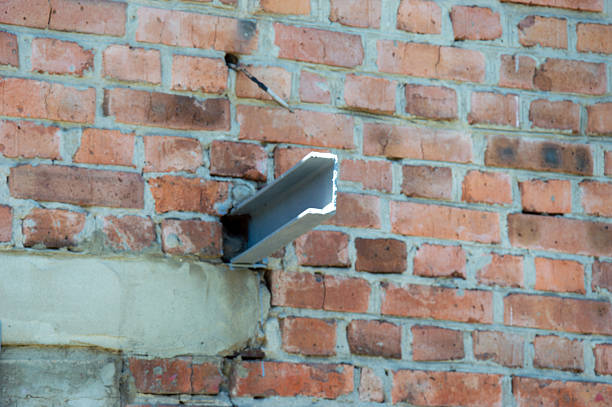 A metal pipe extends from a brick wall, revealing ongoing construction work and urban maintenance in a city environment.