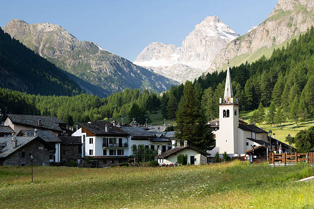 Italy's smallest administrative region, the Aosta Valley, is home to most of the highest peaks in the European Alps. It is so rewarding (and challenging) to hike and climb along its many trails, overlooking some of the most powerful landscapes on earth, including glaciers, green lakes, sharp ridges and majestic overhanging rock faces. Here is Rhemes Notre Dame, the last hamlet of the Rhemes Valley in the Gran Paradiso National Park, once the hunting reserve of the Savoy family. In the background's Granta Parei peak. Both the mountain peak of Granta Parei and the village's steeple point to the blue sky.