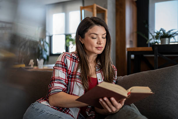 istock Woman reading a book on the sofa at home 2224009556