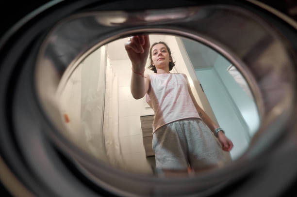 Young woman doing laundry, putting a laundry pod in the washing machine
