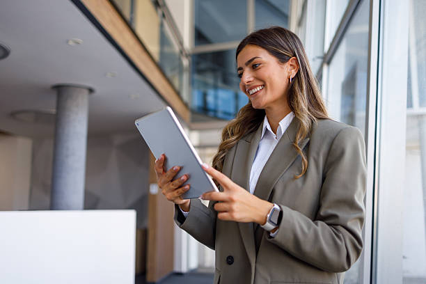 istock Businesswoman browsing on digital tablet, enjoying online work in modern office space, representing connection and efficiency in corporate environment 2224010623