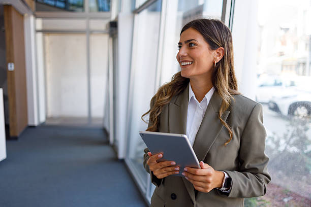 istock Professional female executive striding purposefully in sleek corporate hallway, tablet in hand, radiating confidence and leadership 2224010706