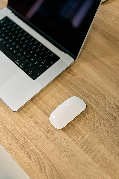 Modern workspace showing a laptop and mouse on a wooden desk, ideal for remote work or home office setups