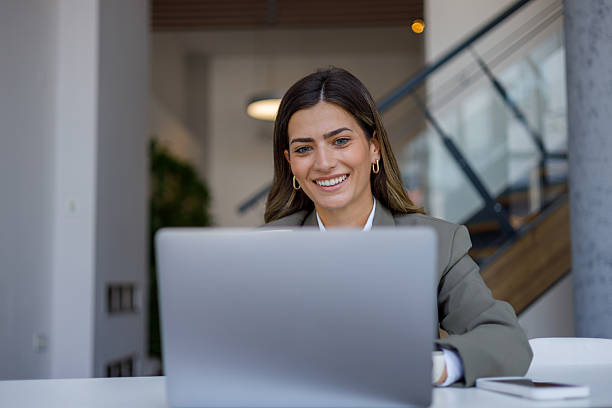 istock Professional businesswoman smiling while working on laptop in contemporary workspace 2224010969