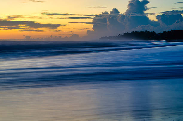Long exposure of a tropical beach at sunset with smooth waves creating a relaxing and dreamy atmosphere