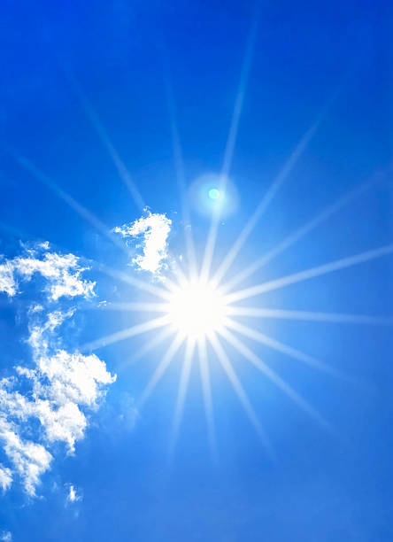 istock Bright sun with beautiful sunbeams shining through a clear blue sky with wispy clouds 2224013568