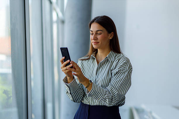 istock Young businesswoman engaging with her smartphone inside a modern office building, utilizing technology for communication and networking 2224013841
