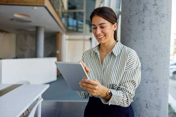 istock Young businesswoman smiling while using a digital tablet in a sleek, modern office, embodying professionalism and connectivity 2224014845