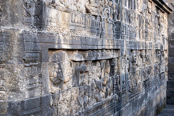istock Ancient stone wall carvings with intricate figures line a temple corridor. 2224015335