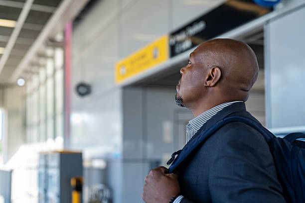 A black senior professional is checking the departure times at a transit station.  This was taken at University of Washington Transit station in Seattle Washington state.