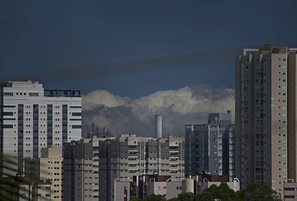 urban skyline with buildings illuminated by afternoon light, under a blue sky with thick clouds - MOGI DAS CRUZES,  SAO PAULO,  BRAZIL.