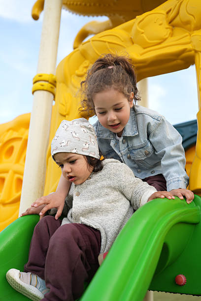 istock Two Young Sisters on a Playground Slide, Close-up 2224023318