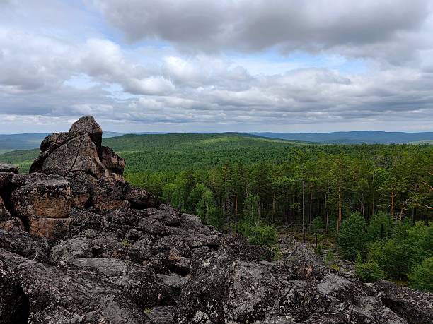 istock scenic view from rocky summit overlooking lush green forest under cloudy skies. 2224023825