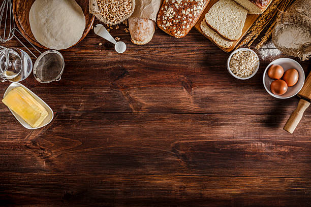 Artisanal bakery:  Dough and bread ingredients and utensils on cutting board frame in a rustic kitchen.