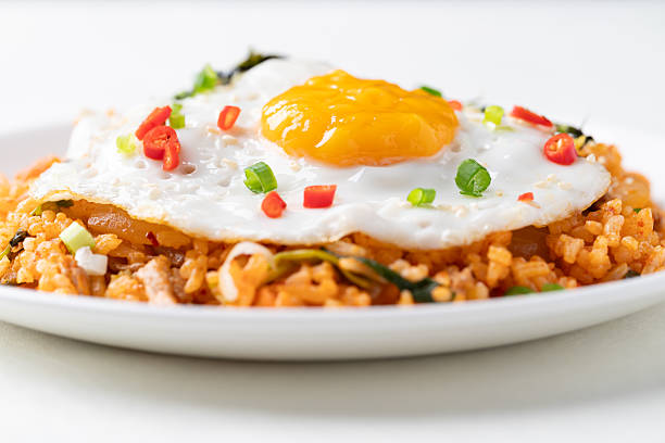 Kimchi fried rice with fried egg, pork, sesame seed, chili, spring onion and seaweed on white plate, Korean food