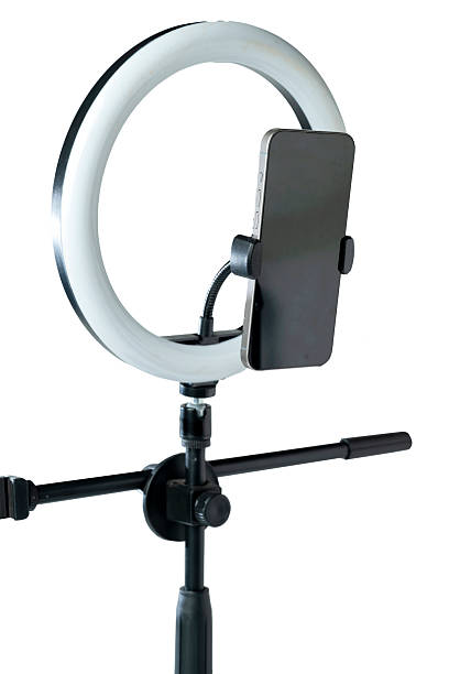 istock Round LED ring light with a cellphone on a phone holder isolated over a white background. Vlogging or live streaming equipment. Mockup or Copy space 2224031022