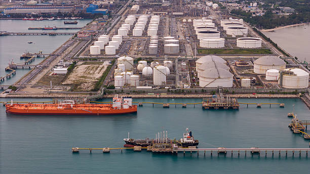 istock large oil tanker docked at a refinery terminal with multiple white storage tanks, complex pipeline networks, and offshore loading platforms. Represents global oil logistics 2224034013