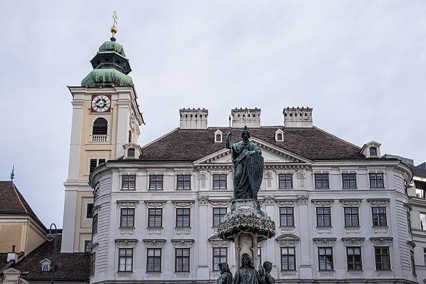 Vienna, Austria – Austriabrunnen (Austria Fountain) with Schottenstift (Scottish Monastery) in background, neoclassical allegory before Baroque abbey on Freyung.