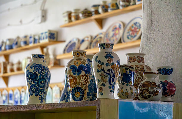 istock Hand-painted ceramic vessels on display in a shop or workshop – jugs, vases, and cups with folk patterns, set against shelves filled with decorative plates and pottery. 2224040901