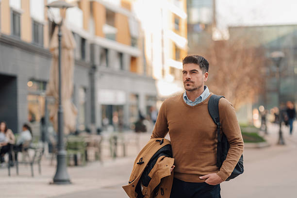 istock Confident businessman walking down city street carrying jacket and backpack 2224043807