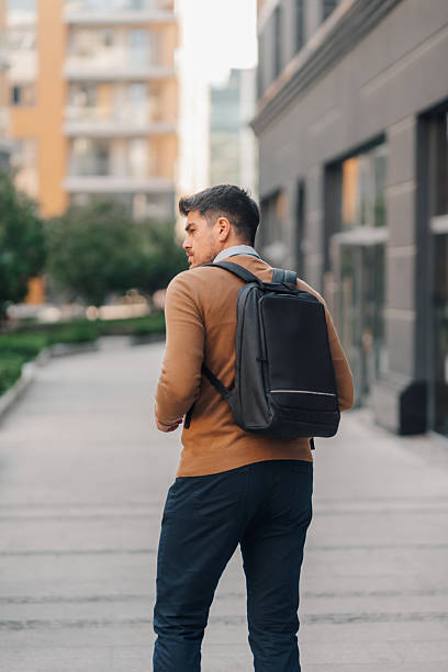 istock Businessman walking in the city with backpack looking over shoulder 2224043888