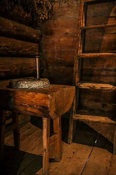 istock Rustic log-cabin interior with sturdy wooden chopping block supporting stone hand mill, highlighting traditional rural grain-grinding craftsmanship in warm, low light 2224046027