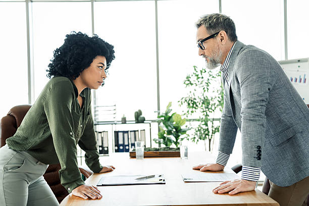 istock Professional coworkers engaged in a discussion at a modern office workspace with natural daylight and vibrant interior. 2224049661