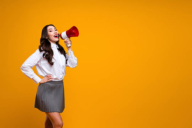 istock Charming young woman speaking into a megaphone against a vibrant orange background 2224050167
