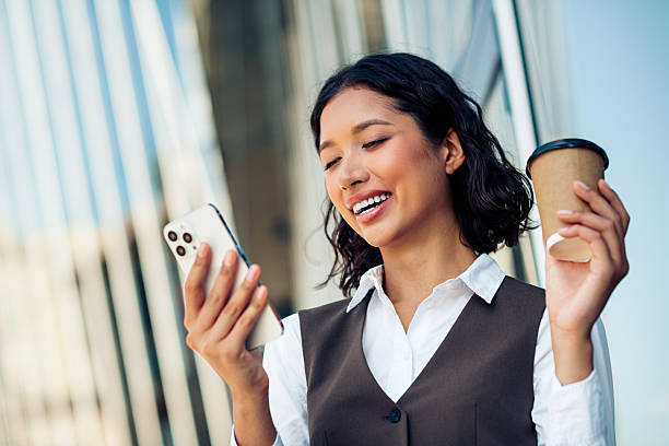 istock Confident professional woman enjoying a coffee break while engaging with her smartphone in a bustling urban environment 2224051076
