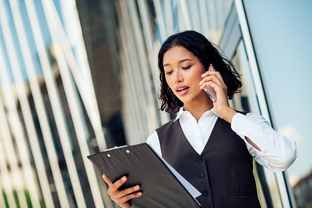 istock Confident young businesswoman multitasking with a phone call and documents in a professional attire outdoors 2224051108