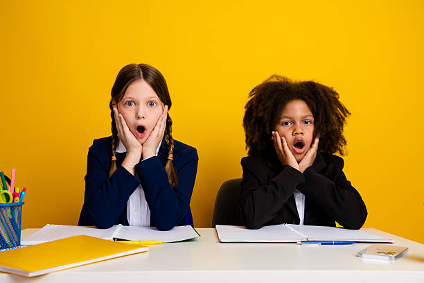istock Diverse schoolgirls surprised in classroom with notebooks and yellow background, expressing emotions, preteen education 2224053992