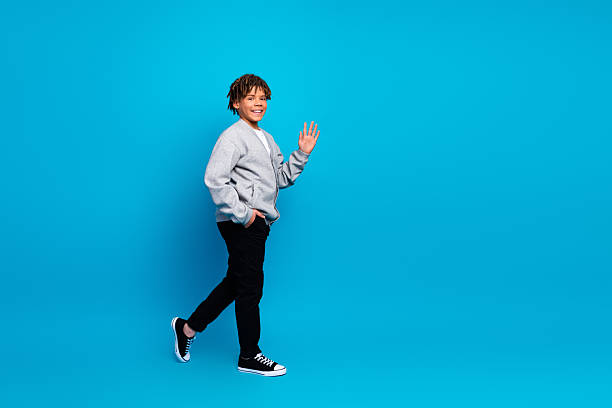 istock Smiling Young Boy in Gray Jacket Posing Against Vibrant Blue Backdrop 2224054108