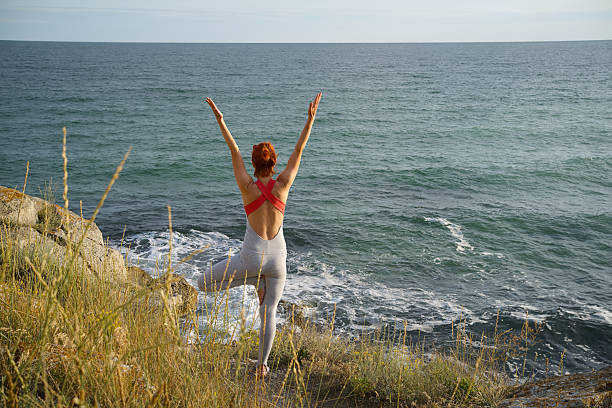 istock Woman Practicing Yoga Tree Pose Facing the Sea 2224054762