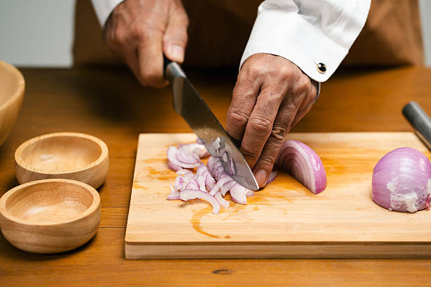 istock Close up of hands slicing onion on cutting board in kitchen. 2224055176