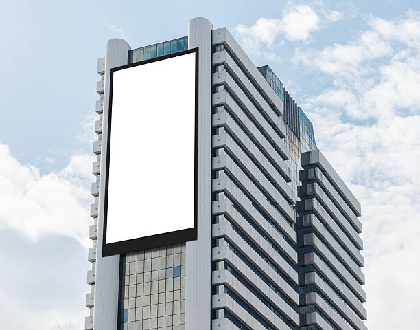 istock Mock up white vertical large LED display billboard on tower building with blue sky background .Clipping path for mockup 2224059459