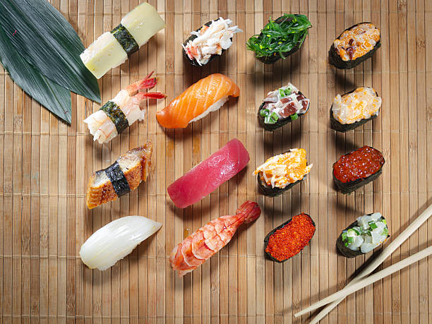 A variety of sushi rolls are displayed on a bamboo tray