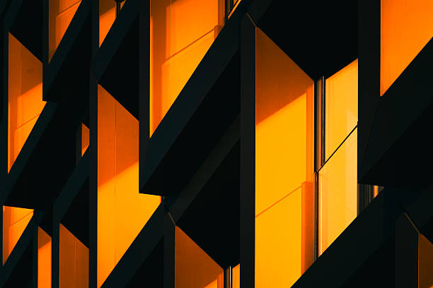 Close-up of modern architectural detail with interlocking orange metal frames in dramatic shadow