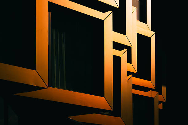Close-up of modern architectural detail with interlocking orange metal frames in dramatic shadow, modern architecture concept