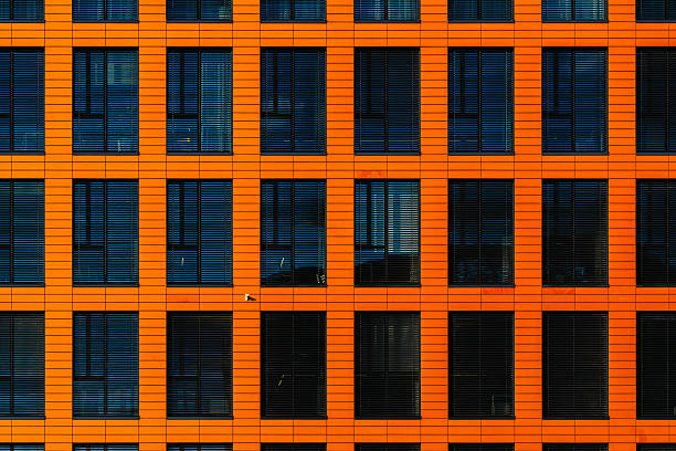 istock Modern office facade with orange cladding and dark blinds forming a repetitive geometric grid 2224063958