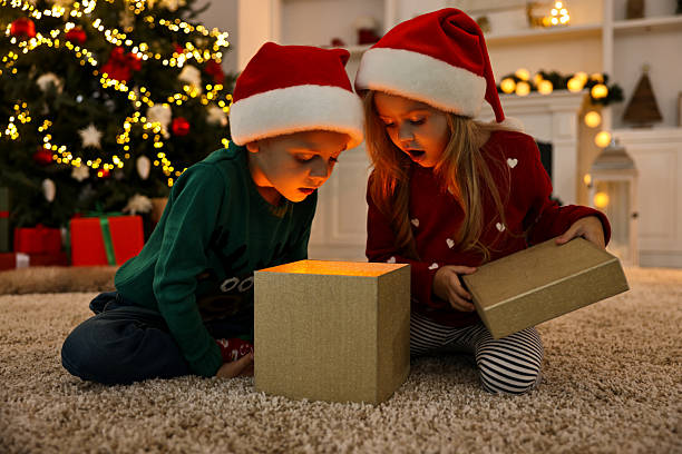 istock Little kids opening magic Christmas box on floor at home 2224065569