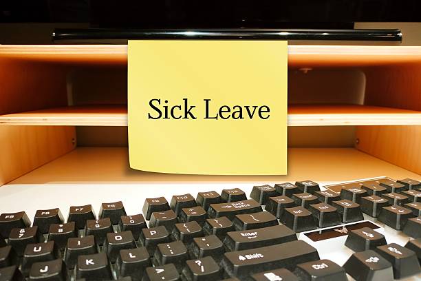 Office wall with stick note written I'M ON SICK LEAVE -  Employee takes time away from work of illness -note worker left to inform he is absent from job due to an illness, injury or accident